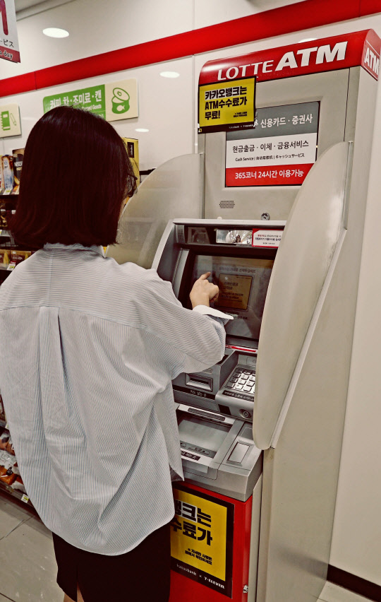 세븐일레븐과 롯데멤버스가 제3인터넷전문은행에 도전한다. 사진은 세븐일레븐 ATM을 이용하는 소비자. <세븐일레븐 제공>